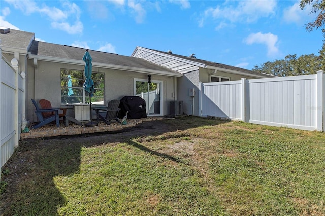 rear view of house featuring stucco siding, a lawn, and fence