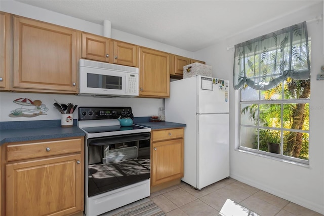 kitchen featuring light tile patterned floors, dark countertops, and white appliances