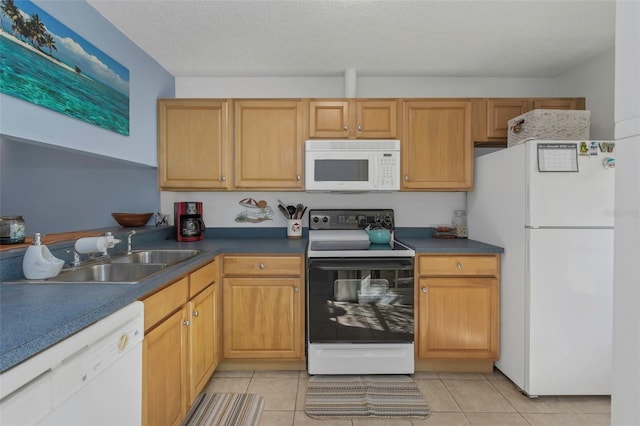 kitchen with dark countertops, white appliances, a sink, and light tile patterned flooring