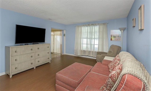 living room featuring visible vents, a textured ceiling, baseboards, and wood finished floors
