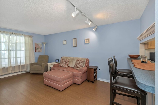 living room with track lighting, a textured ceiling, baseboards, and wood finished floors