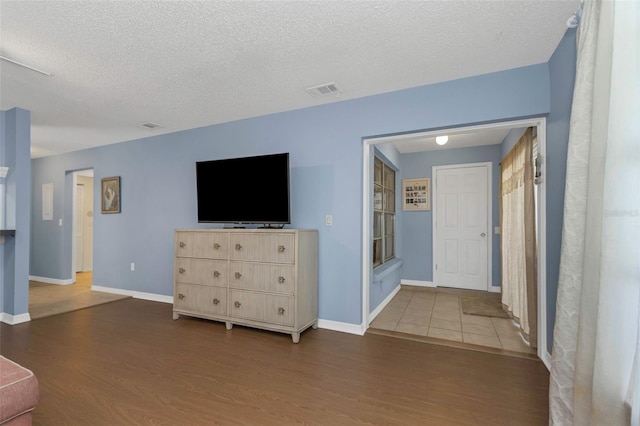 living area with visible vents, a textured ceiling, baseboards, and wood finished floors