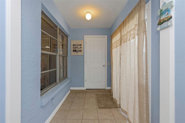 hallway featuring tile patterned floors and baseboards
