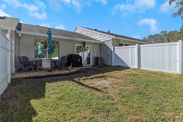 rear view of house with stucco siding, fence, and a lawn