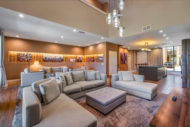 living room with wood-type flooring, sink, a high ceiling, and an inviting chandelier