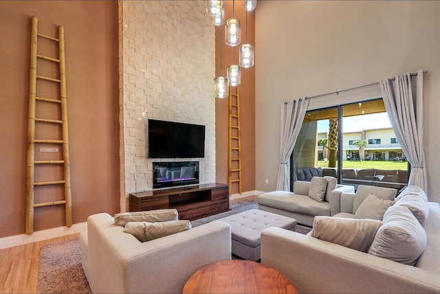 living room with wood-type flooring, a fireplace, and a towering ceiling