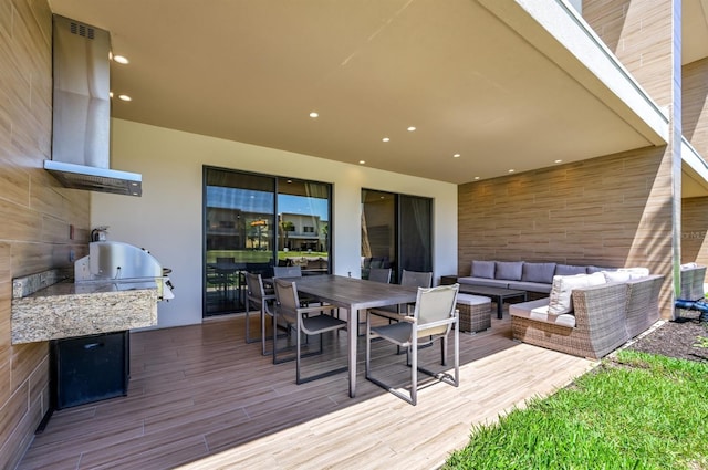 wooden terrace featuring a grill, an outdoor living space, and exterior kitchen