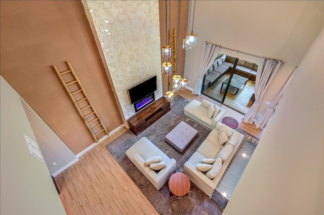 living room with a stone fireplace, wood-type flooring, and a high ceiling