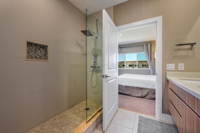 bathroom with tile patterned flooring, vanity, and tiled shower