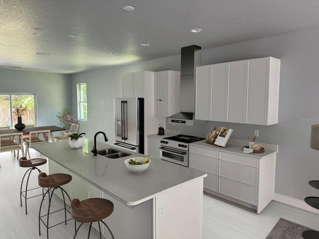 kitchen featuring a kitchen island with sink, high end refrigerator, a sink, a kitchen breakfast bar, and white range with gas cooktop