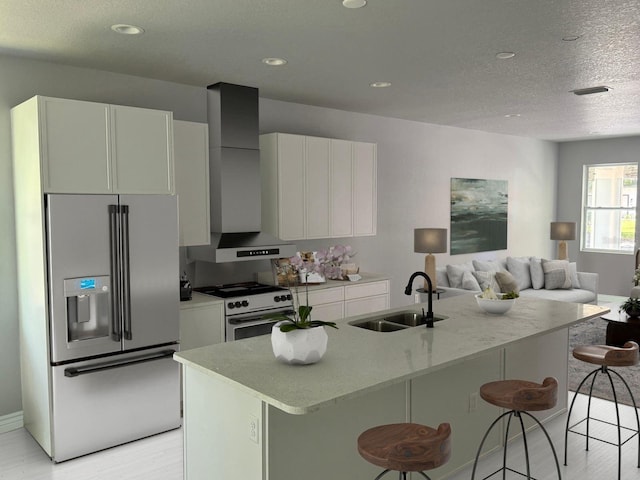 kitchen featuring stainless steel refrigerator with ice dispenser, white cabinetry, a sink, white range with gas cooktop, and wall chimney exhaust hood