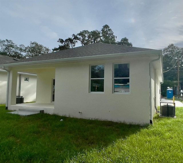 view of property exterior with central AC unit, a lawn, and stucco siding