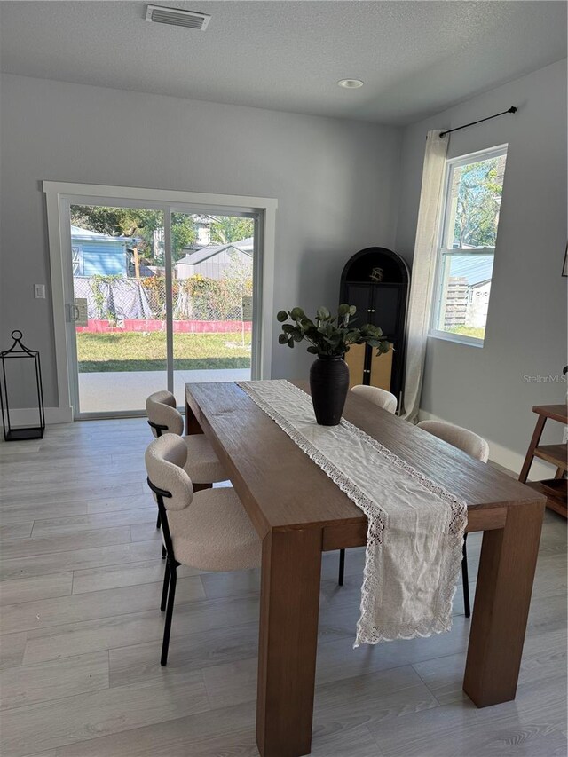 dining room with visible vents, a textured ceiling, and wood finished floors