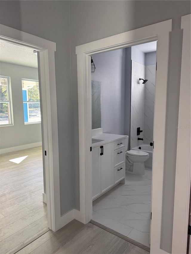 full bath with baseboards, bathing tub / shower combination, toilet, wood finished floors, and vanity