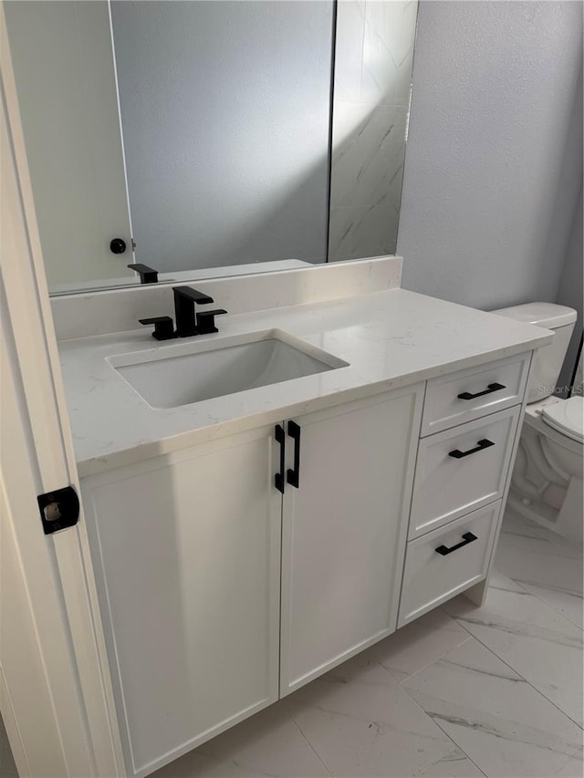 half bath featuring toilet, marble finish floor, and vanity