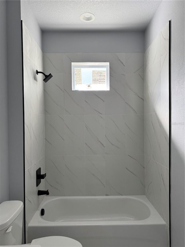 bathroom featuring bathtub / shower combination, a textured ceiling, and toilet