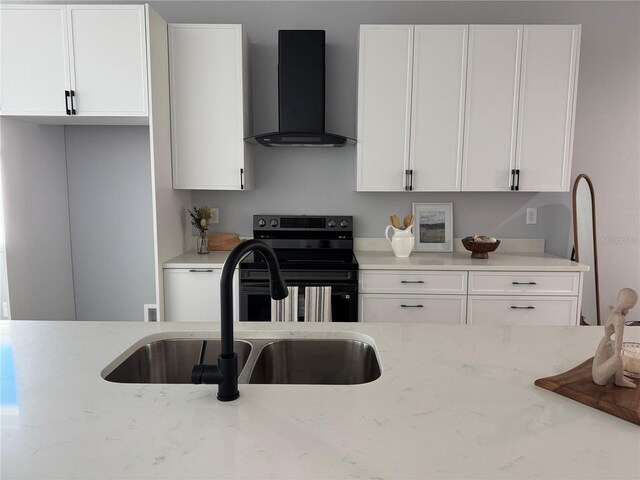 kitchen with a sink, white cabinets, light stone countertops, electric range oven, and wall chimney exhaust hood