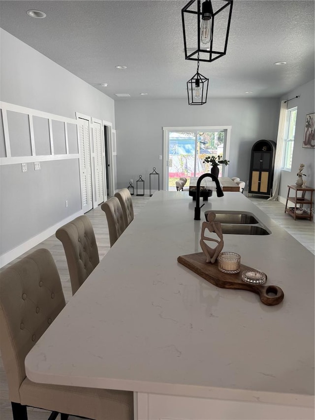 dining space with a wealth of natural light, a textured ceiling, and baseboards