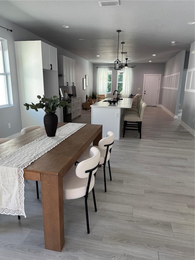 dining space featuring a wealth of natural light, visible vents, a textured ceiling, and baseboards