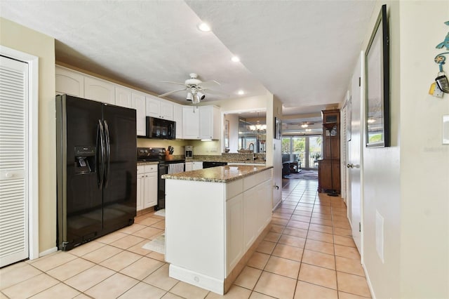 kitchen with light tile patterned floors, white cabinetry, dark stone countertops, and black appliances