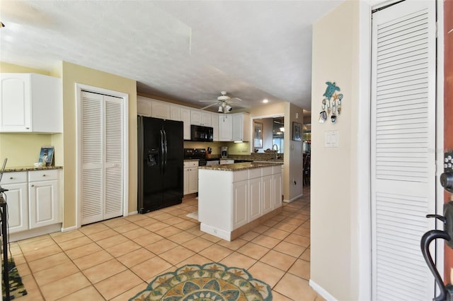 kitchen featuring white cabinets, light tile patterned floors, dark stone counters, and black appliances