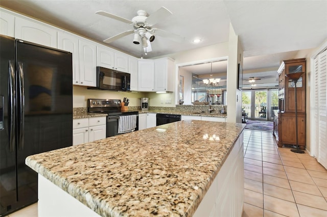 kitchen with white cabinetry, light tile patterned floors, black appliances, and ceiling fan with notable chandelier