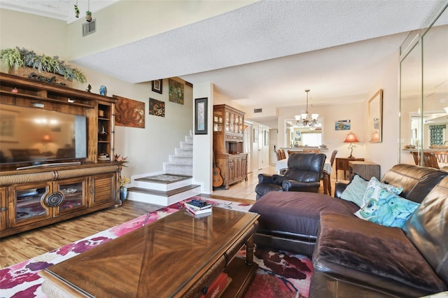 living room featuring light wood-type flooring, a textured ceiling, and a notable chandelier