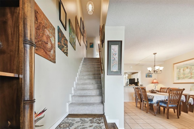 stairs with tile patterned floors, a textured ceiling, and an inviting chandelier