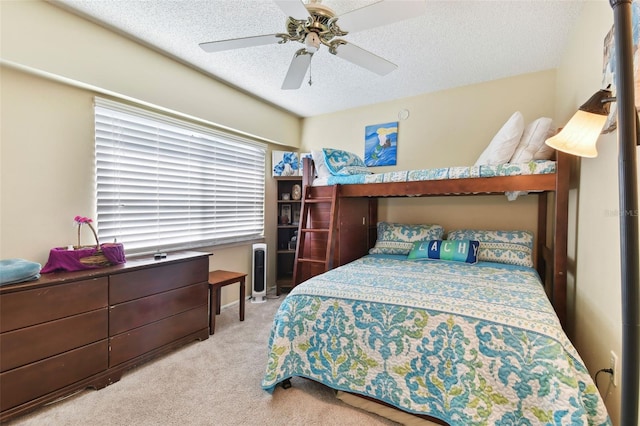 bedroom with ceiling fan, light colored carpet, and a textured ceiling