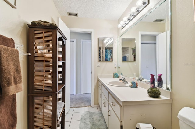 bathroom with tile patterned flooring, vanity, a textured ceiling, and toilet