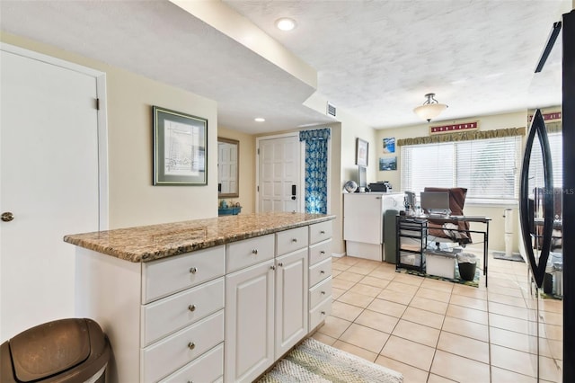 kitchen with light stone countertops, white cabinets, light tile patterned flooring, and a textured ceiling