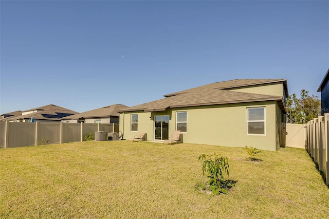 rear view of house with a yard and central AC unit