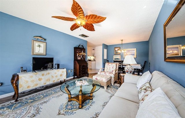 living room with hardwood / wood-style floors and ceiling fan with notable chandelier