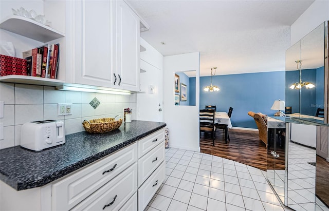 kitchen with light hardwood / wood-style flooring, a chandelier, pendant lighting, decorative backsplash, and white cabinets