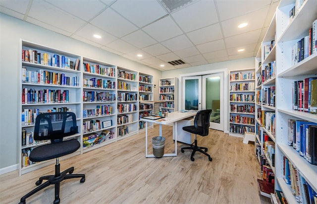 home office featuring built in shelves, a paneled ceiling, and light hardwood / wood-style flooring