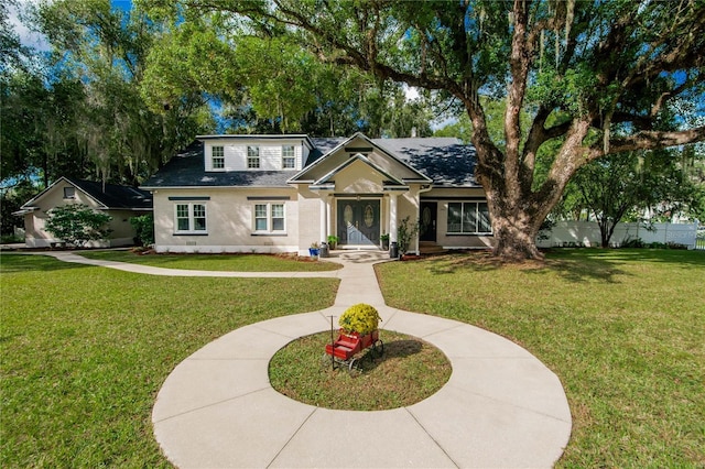 view of front facade featuring a shingled roof, fence, and a front lawn