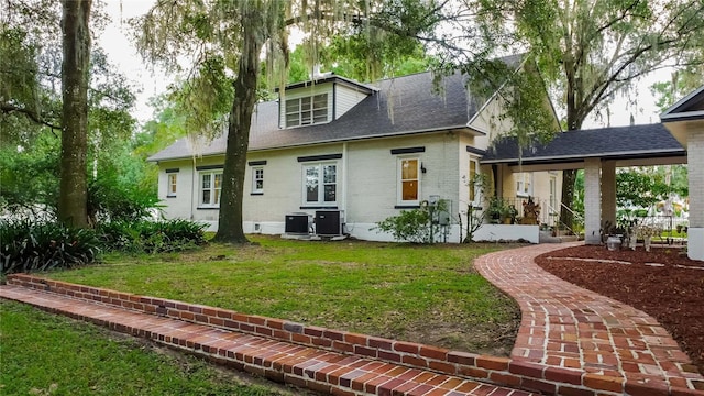 rear view of property with a lawn and central air condition unit