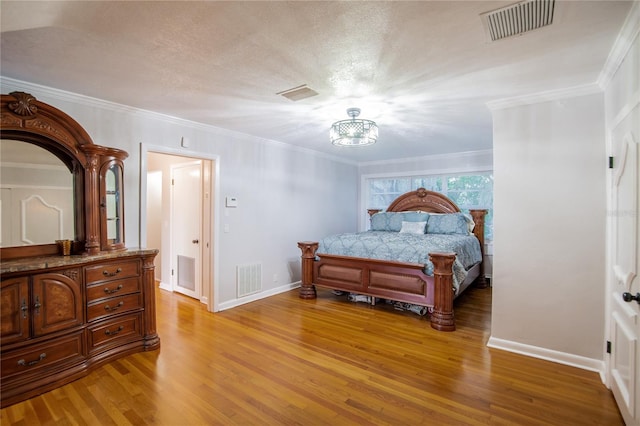 bedroom with hardwood / wood-style floors, ornamental molding, and a textured ceiling