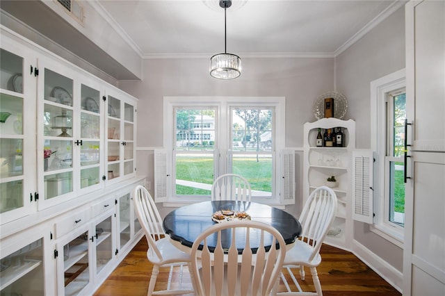 dining space featuring dark wood-style flooring, an inviting chandelier, and crown molding