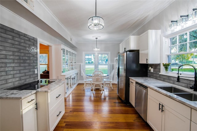 kitchen featuring white cabinetry, crown molding, decorative light fixtures, stainless steel appliances, and a sink