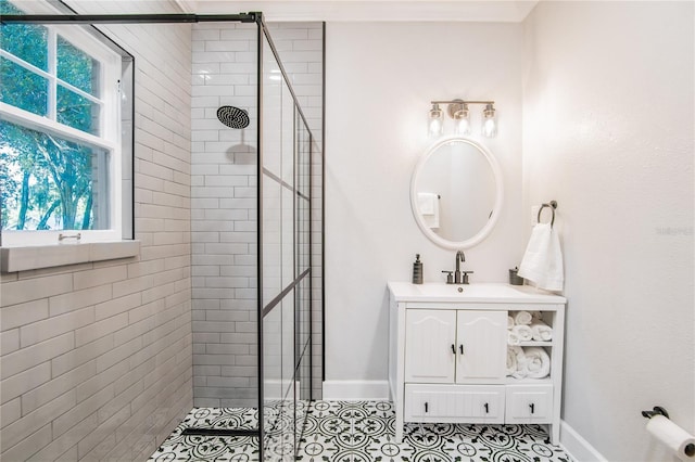 bathroom with a tile shower, tile patterned flooring, baseboards, and vanity