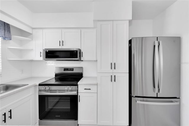 kitchen with decorative backsplash, appliances with stainless steel finishes, and white cabinetry