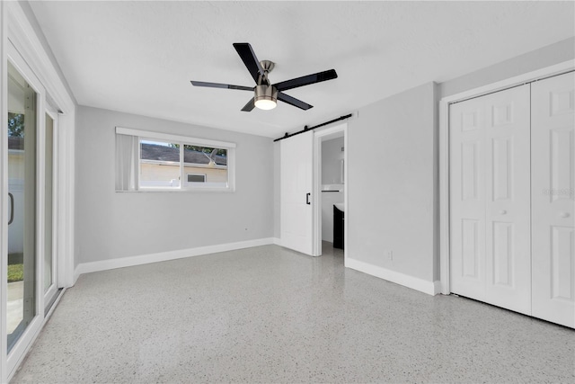 unfurnished bedroom featuring a barn door, a closet, and ceiling fan