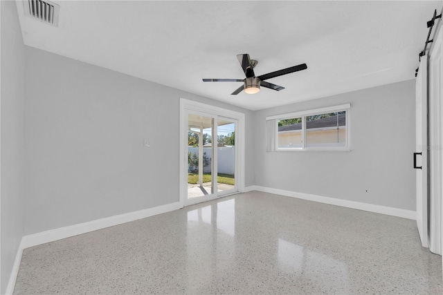 unfurnished room featuring a barn door and ceiling fan