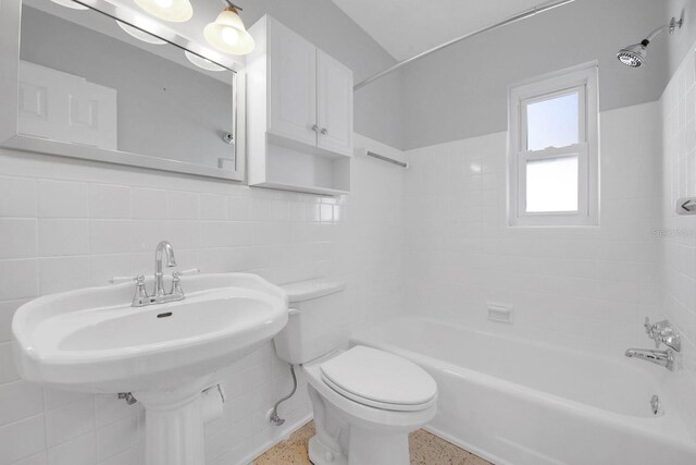 bathroom featuring tiled shower / bath, tasteful backsplash, toilet, and tile walls