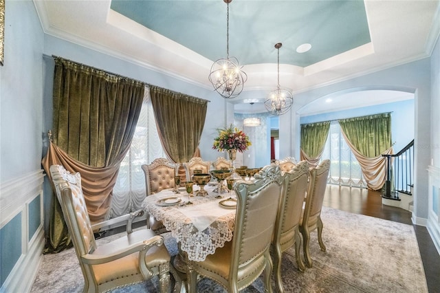 dining area with ornamental molding, a notable chandelier, and a tray ceiling