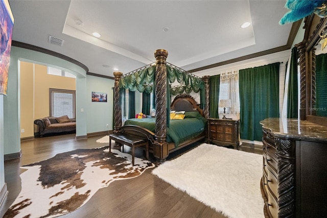 bedroom featuring a raised ceiling, crown molding, and dark hardwood / wood-style floors