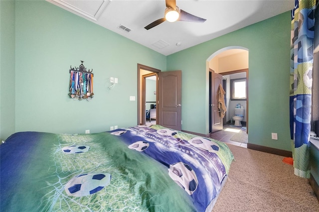 bedroom featuring light carpet, ceiling fan, and ensuite bathroom