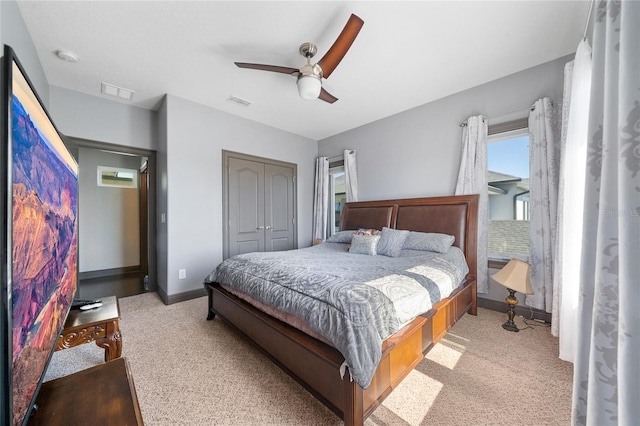 bedroom featuring multiple windows, light colored carpet, a closet, and ceiling fan