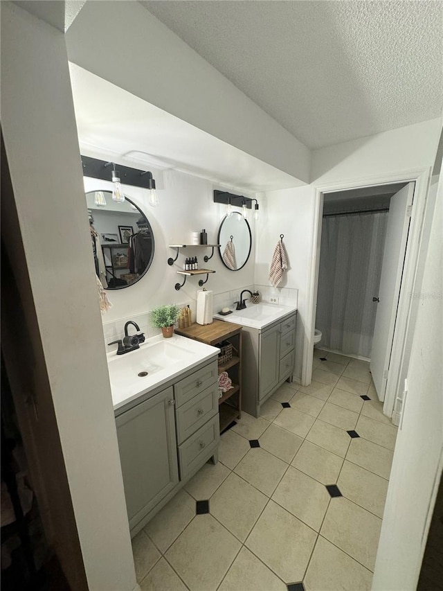 bathroom featuring toilet, a textured ceiling, vanity, and tile patterned floors